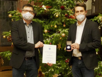 Roman Wagner und OB Conradt mit Urkunde und Medaille vor Weihnachtsbaum im Rathausfestsaal
