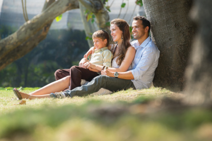 Eltern und Kind sitzen unter einem Baum