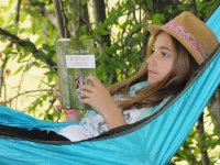 Mädchen liest Buch in einer Hängematte
