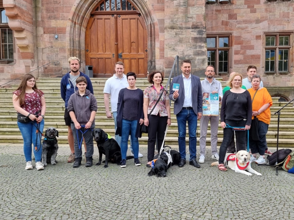 Teilnehmerinnen und Teilnehmer beim Start der Kampagne "Assistenzhund Willkommen" vor dem Rathaus St. Johann
