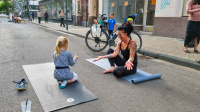 Eine Frau macht mit einem Kind Yogaübungen auf der Sommerstraße.
