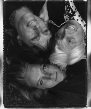 3 Frauen verschiedener Generationen, liegen Kopf an Kopf und lachen