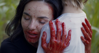 Frau mit Blut an den Händen und im Gesicht umarmt Kind