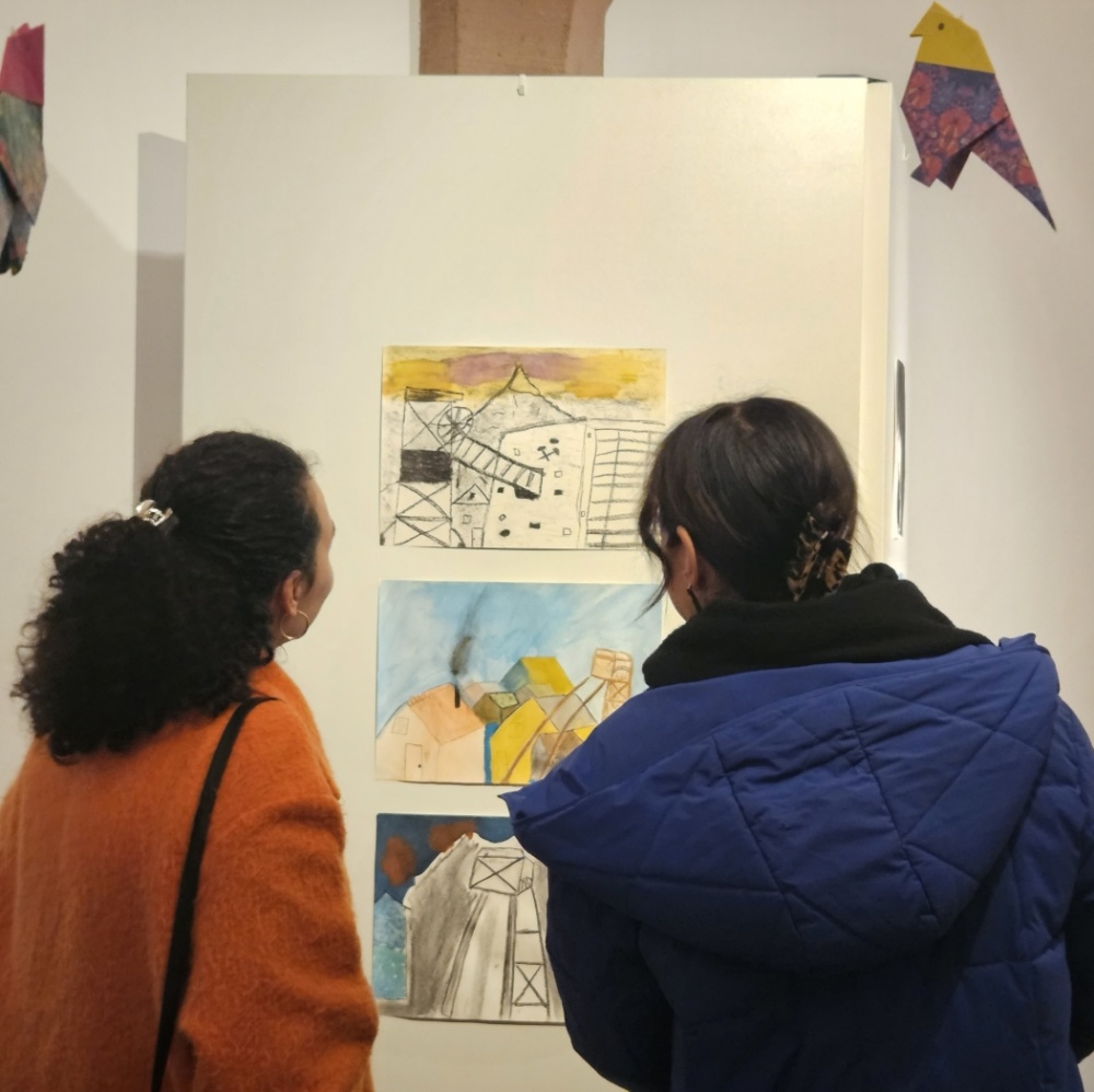 Besucherinnen vor Stellwand mit drei Kinderzeichnungen