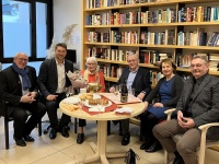 Sechs fröhlich lächelnde Personen um einen Tisch mit Cremant und Laugengebäck. OB Uwe Conradt hät einen Blumenstrauß für eine neben ihm sitzende Seniorin.