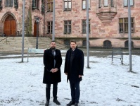 Zwei formell gekleidete Männer im Schnee vor dem Rathaus