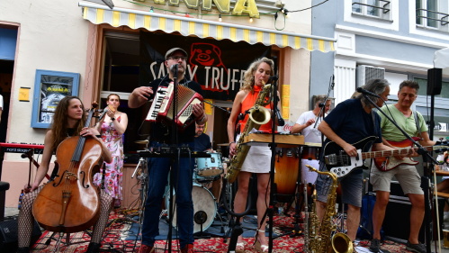 Eine Band mit acht MusikerInnen – unter anderem Cello, Akkordeon, Saxophon, Gitarre, Bass und Schlagzeug – vor der Kneipe Tante Anna