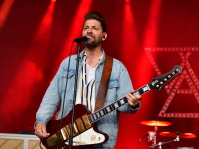 Sänger von Welshly Arms auf der Bühne, mit roten Lichtstrahlern