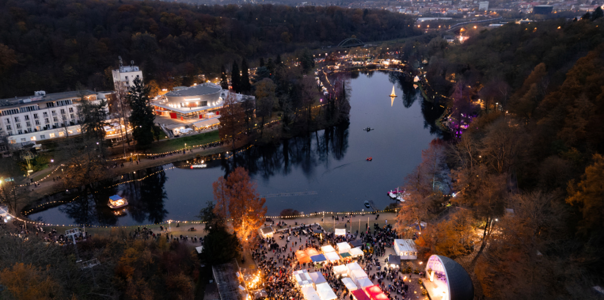 Blick von oben auf den Deutschmühlenweiher mit beleuchteten Ständen und der Seebühne