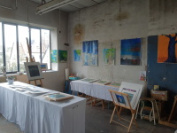 Atelier in der alten Modellschreinerei mit Gemälden an der Wand und zwei Auslagetischen