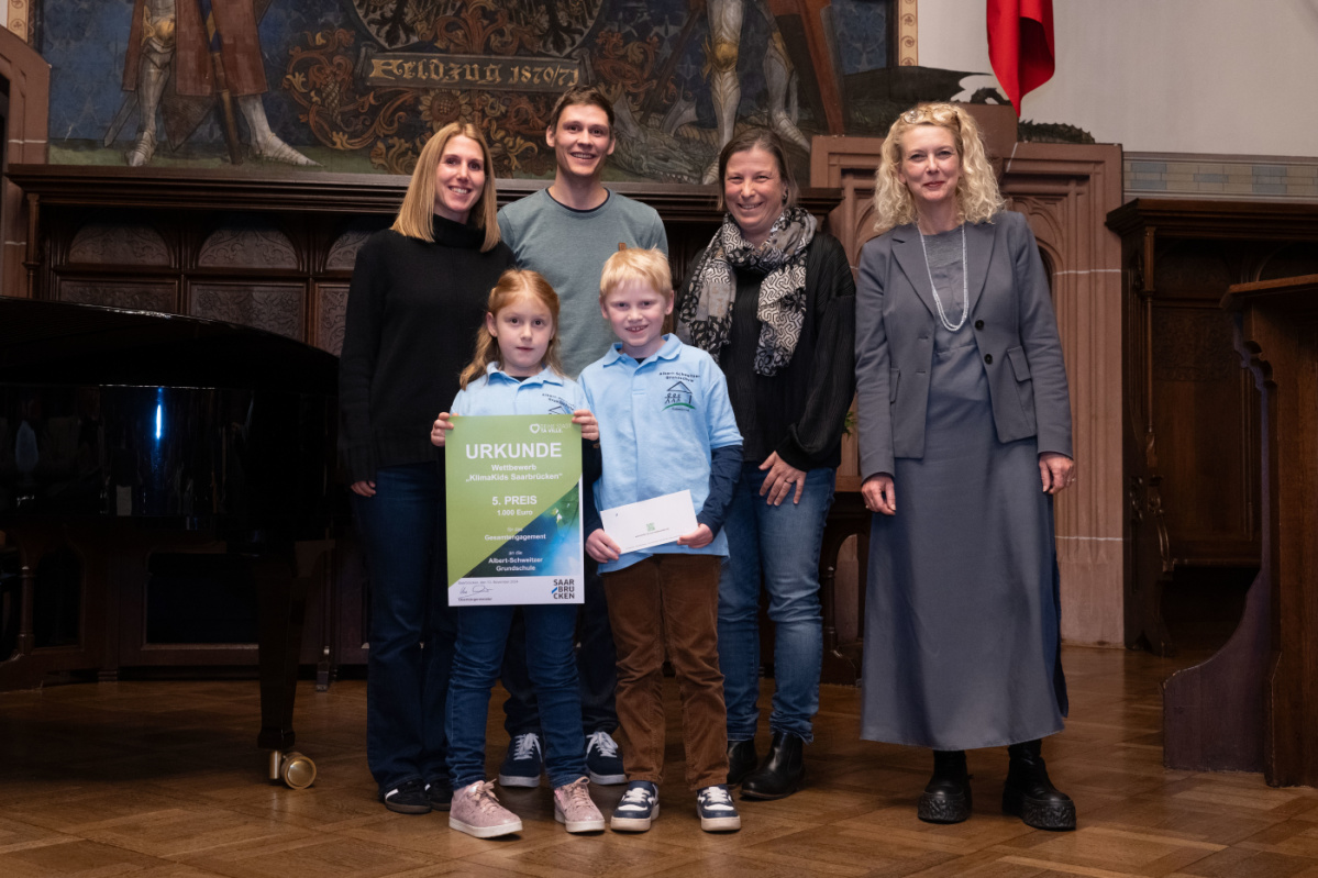 Preisübergabe des fünften Platzes an die Grundschule Albert Schweitzer. Zu sehen sind zwei Schüler welche die Urkunde halten und zwei Betreuer der Grundschule, sowie zwei Jurymitglieder.