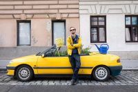 Ein Mann steht vor einem gelben Cabrio. In dem Auto liegen planzen und ein Schild mit der Beschriftung "Wien du bist ein Parkplatz"