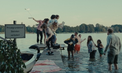 Eine Gruppe Menschen auf und neben einem Steg im Wasser. Man sieht ein Schild, auf dem "Privatgrundstück. Betreten verboten" steht.