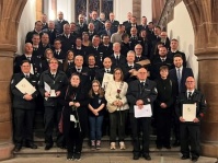 Mehrere Personen, teils in Uniform, stehen auf einen Treppe. Einige davon haben Rosen oder ein Schriftstück in den Händen.