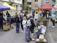 Eine Menschengruppe steht auf einer geschmückten Straße zwischen bunten Pavillions