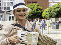 Eine Frau mit hellem Hut spielt Akkordeon auf der Straße