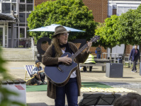 Eine Frau mit Hut spielt Gitarre auf der Straße