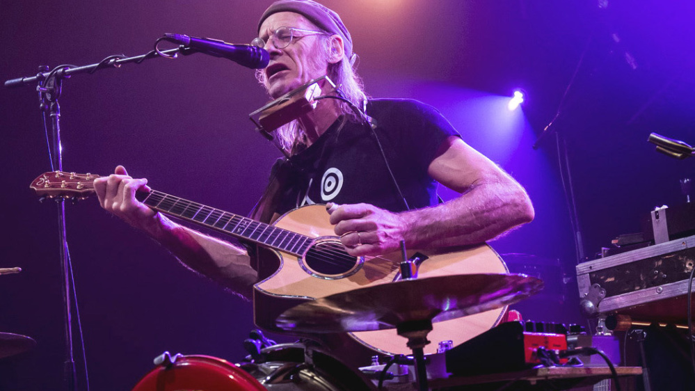 Philippe Ménard Ein Mann am Schlagzeug und Gitarre in der Hand