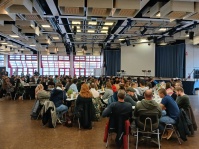 Ein Mann hält vor einem vollen Saal eine Rede