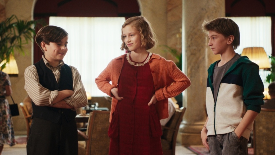 Zwei Jungen und ein Mädchen stehen zusammen in einer Hotellobby. Zwei Jungen und ein Mädchen stehen zusammen in einer Hotellobby.