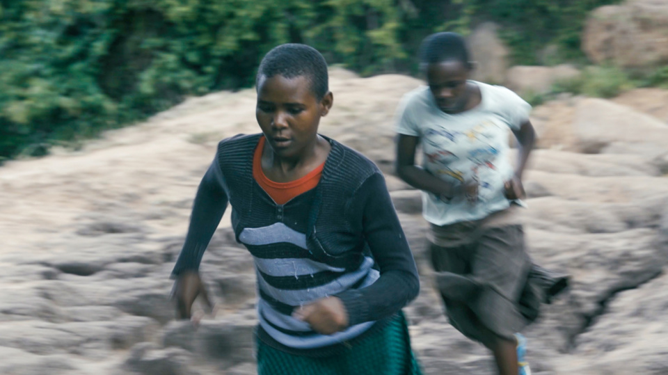 Zwei junge Mädchen rennen über unebenes, steiniges Gelände im Freien. Zwei junge Mädchen rennen über unebenes, steiniges Gelände im Freien.