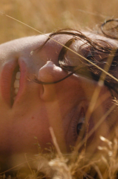 MAJA Eine braunhaarige Frau liegt in einem Feld.