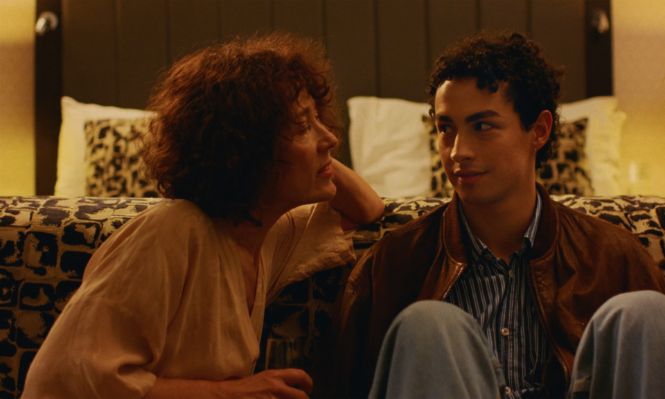 Eine Frau und ein Mann sitzen nebeneinander vor einem Bett und unterhalten sich. Eine Frau und ein Mann sitzen nebeneinander vor einem Bett und unterhalten sich.