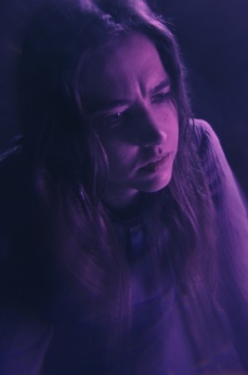 Eine Frau befindet sich in einem in violettes Licht getauchten Raum.