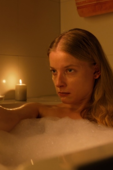 ALS WÄRE ES LEICHT Eine Frau sitzt in der Badewanne. Sie hält eine Plastikpistole in den Händen und zielt damit vor sich.