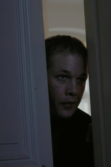 Ein Mann schaut durch einen Türspalt.