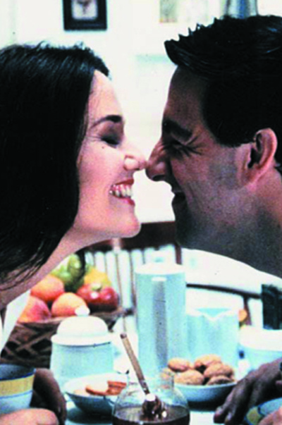 Eine Frau und ein Mann neigen sich zueinander über einen gedeckten Frühstückstisch.