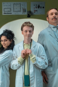 Eine Frau, einer junger und ein älterer Mann stehen zusammen und schauen in die Kamera. Sie tragen weiße Arztkittel.