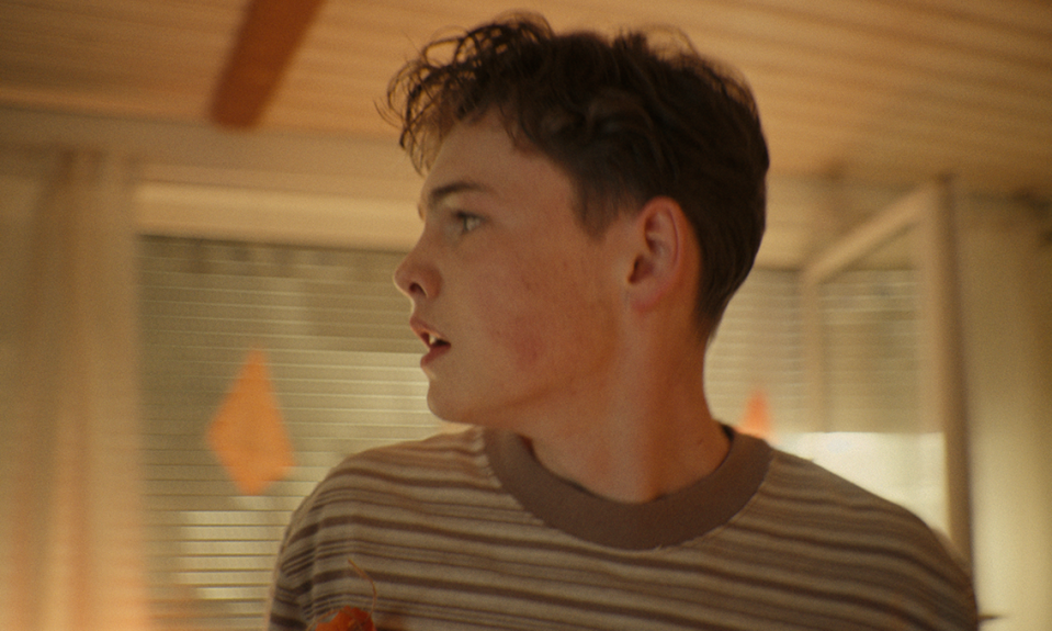 Ein Jugendlicher steht in einem Zimmer vor einem geöffneten Fenster.