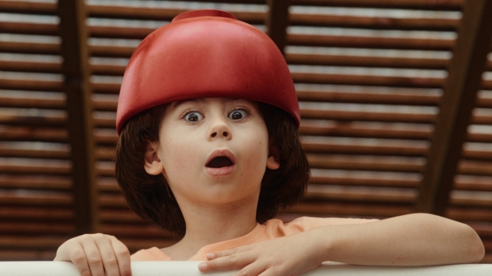 Ein Kind schaut erschrocken über ein Geländer. Es trägt eine rote Kopfbedeckung. Ein Kind schaut erschrocken über ein Geländer. Es trägt eine rote Kopfbedeckung.