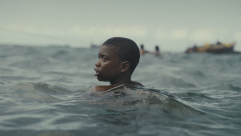 Ein Junge schwimmt im Meer. Im Hintergrund ist ein Boot zu sehen. Ein Junge schwimmt im Meer. Im Hintergrund ist ein Boot zu sehen.