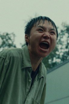 Eine junge Person steht durchnässt draußen und schreit. 