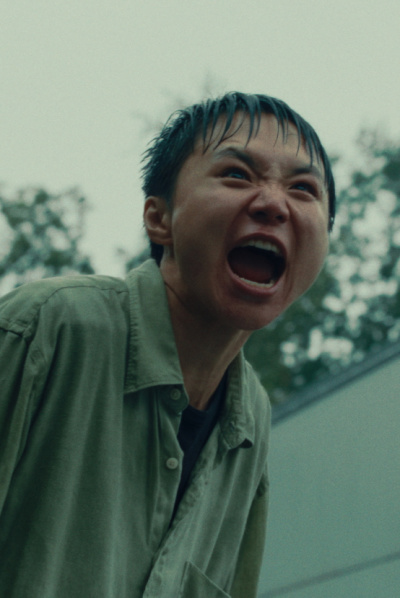 Eine junge Person steht durchnässt draußen und schreit. 