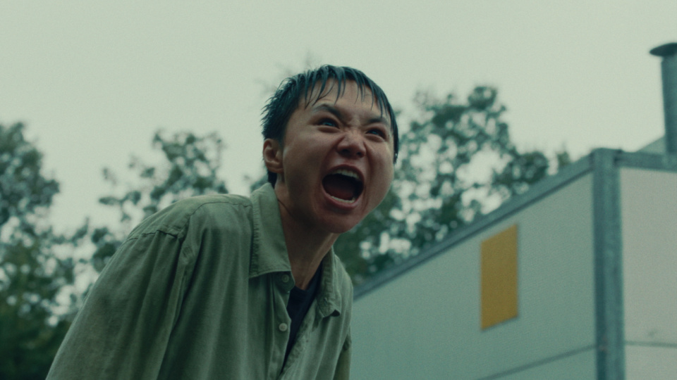 Eine junge Person steht durchnässt draußen und schreit. 