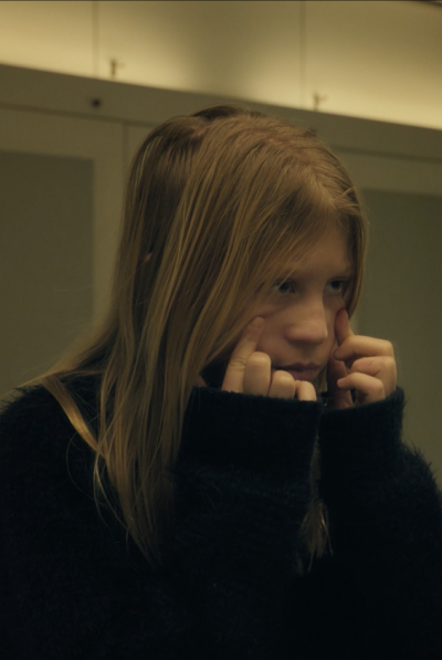 Ein Mädchen steht vorm Spiegel und hält sich im Gesicht.