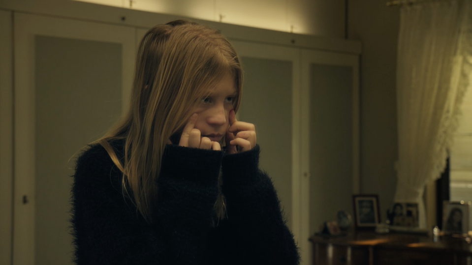 Ein Mädchen steht vorm Spiegel und hält sich im Gesicht.