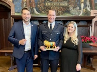 Der Saarbrücker Rekordschwimmer Andreas Waschburger hat sich am 15. Dezember im Beisein seiner Frau in das Goldene Buch der Landeshauptstadt eingetragen Zwei Männer und eine Frau in Anzügen und stehen in einem historischen Saal nebeneinander und posieren für die Kamera. Der Mann in der Mitte hat einen Miniaturlöwen in der Hand