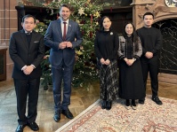 Fünf Personen stehen vor einer geschmückten Weihnachtstanne in einem festlichen Saal