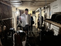 Mann betrachtet Exponate in einem historischen Bunkerraum, während weitere Personen im Hintergrund durch den Gang gehen.