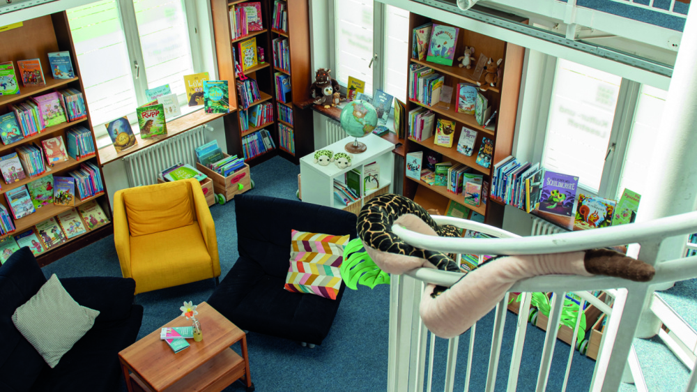 Kultur- und Lesetreff Dudweiler Bücherregale über zwei Etagen mit Wedentreppe und mehreren Sofas
