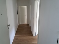 Wohnungsflur mit Zugang zu mehreren Zimmern, Wände und Decken weiß, Vinylboden eichefarben